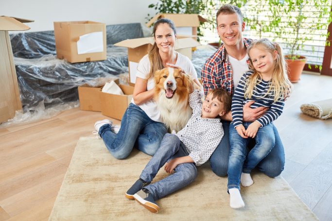 Baufamilie Eine Familie mit zwei Kindern und einem Hund sitzt in einem neu bezogenen Zuhause.