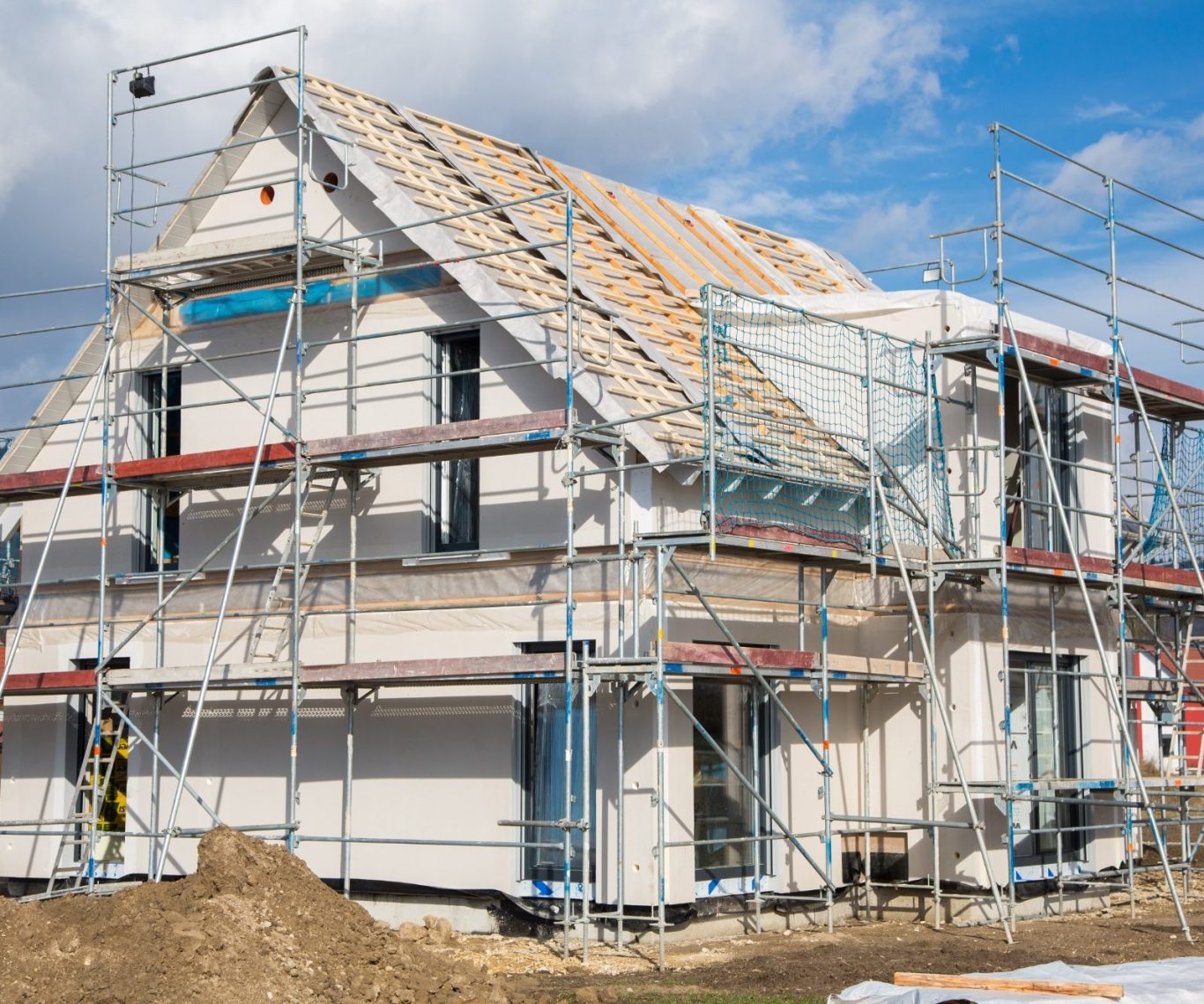 Aufbau Fertighaus Baustelle eines Hauses mit Gerüst, unvollständigem Dach und frischem Putz.