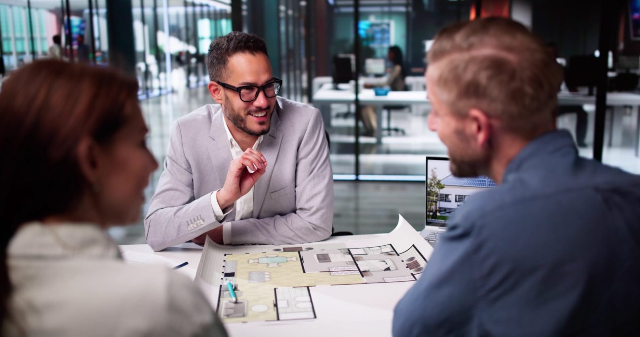 Bauberatung mit Bauherren Drei Personen in einem modernen Büro diskutieren über Pläne und Ideen.