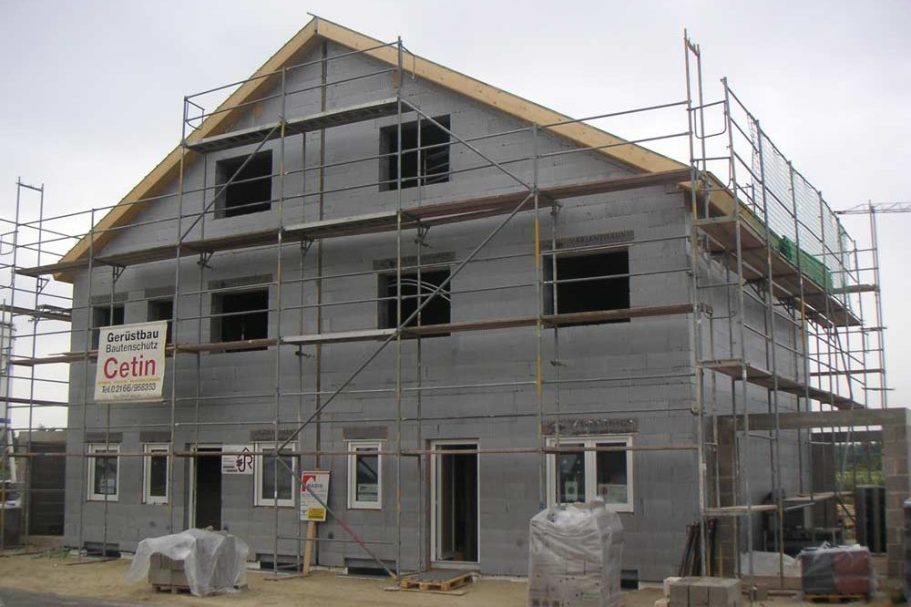 Massivhaus VHG Bausatzhaus Unvollendetes Wohnhaus mit Gerüst und Bauarbeiten, Fenster und Türen fehlen.