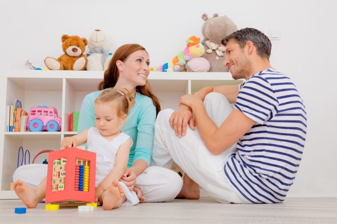Baufamilie Familie spielt gemeinsam auf dem Boden in einem Kinderzimmer mit Spielzeug.